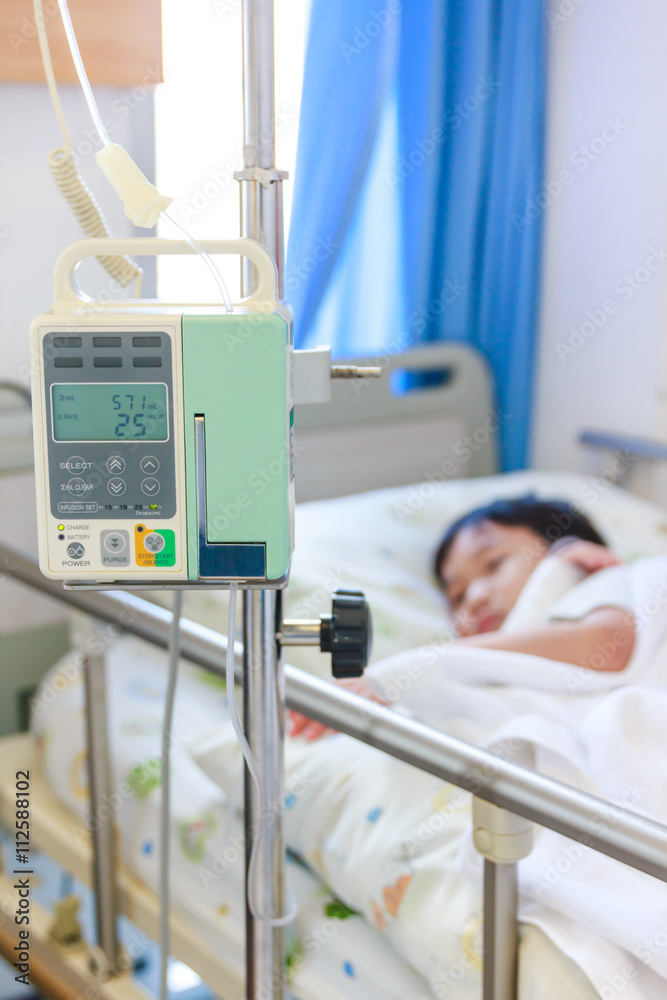 Asian boy lying on sickbed with infusion pump intravenous IV drip
