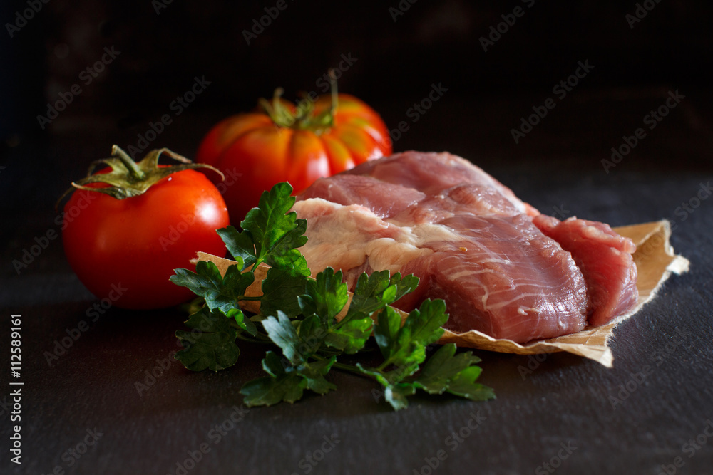 Slice of raw turkey steak with herbs and tomatoes