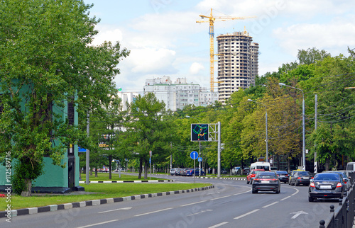 Машины едут по проспекту в Москве на фоне строительства нового жилого комплекса