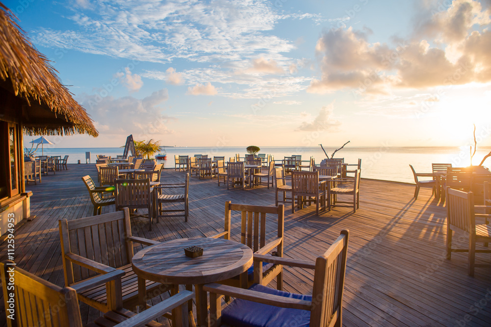 Fototapeta premium Summer empty open air restaraunt near sea at exotic island on beautiful sunset