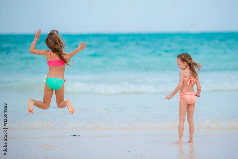 Little girls playing together at shallow water on vacation