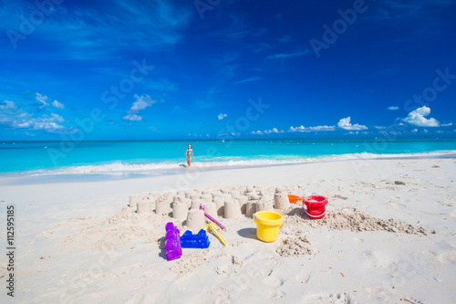 Fototapeta Naklejka Na Ścianę i Meble -  Sandcastle at white beach with plastic kids toys