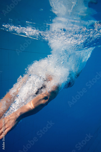 Fototapeta Naklejka Na Ścianę i Meble -  Young man dives into the pool, underwater shot