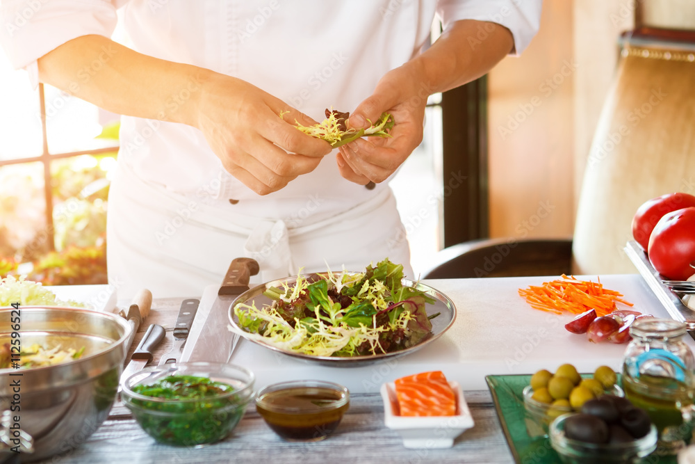 Man's hands holding herbs. Plate with salad. Chef's best recipe. Appetizer is almost ready.