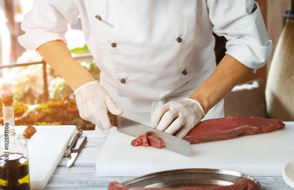 Man cutting meat with knife. Meat lying on cooking board. Preparation of veal in restaurant. Busy morning of skillful chef. Man cutting meat with knife. Meat lying on cooking board. Preparation of veal in restaurant. Busy morning of skillful chef.