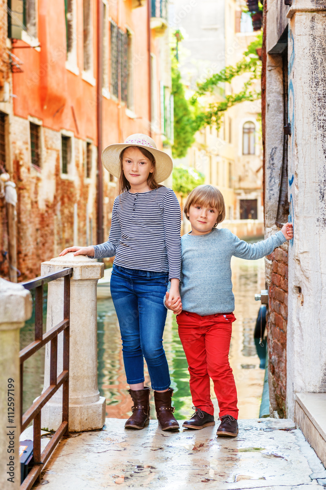 Outdoor portrait of adorable fashion kids visiting Venice, Italy. Little girl and boy walk through the old venetian streets