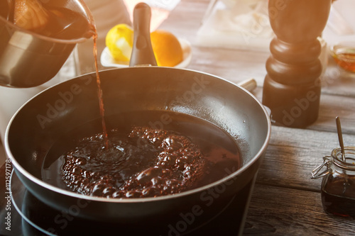 Liquid flowing onto frying pan. Dark liquid boiling on pan. Key ingredient for delicious sauce. Best sort of red wine.