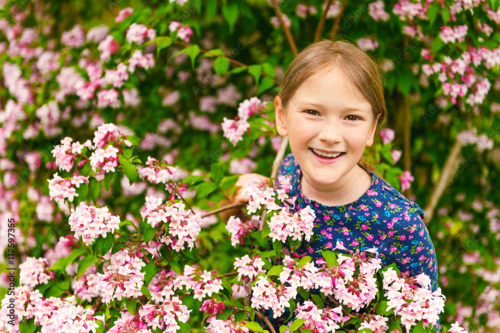 Outdoor portrait of a cute little girl of 8-9 years old, playing with spring flowers Outdoor portrait of a cute little girl of 8-9 years old, playing with spring flowers
