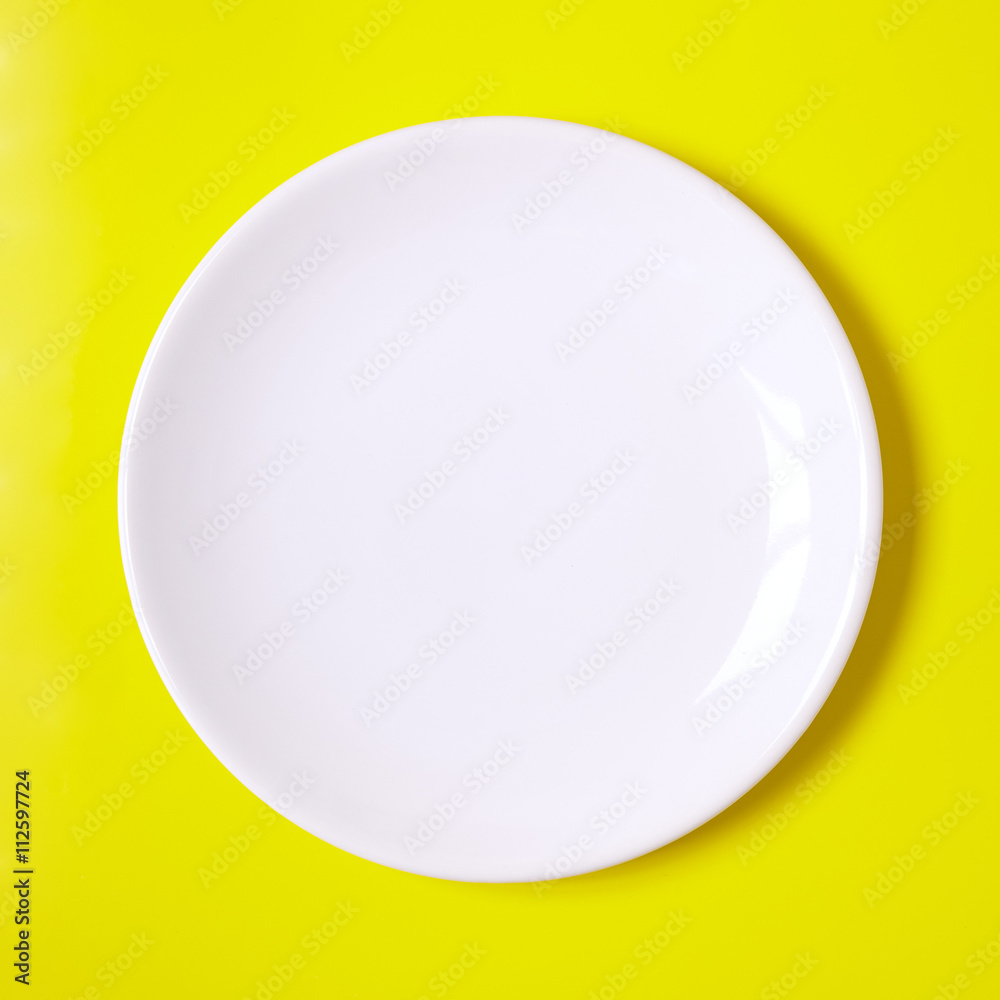 Empty white plate on a yellow background