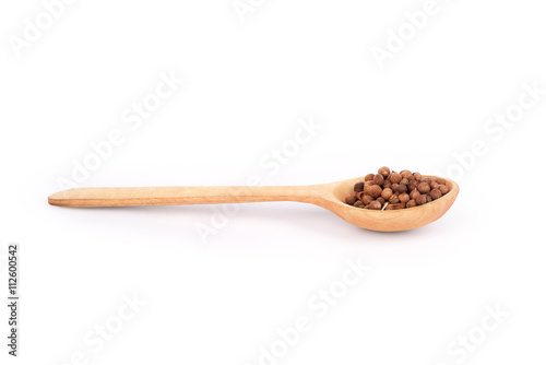 Pepper on a wooden spoon isolated on white