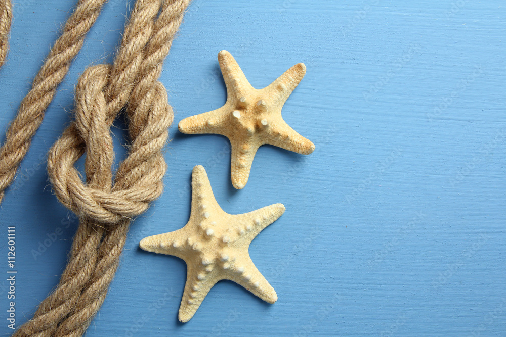 knot with different seashells on blue wooden background knot with different seashells on blue wooden background