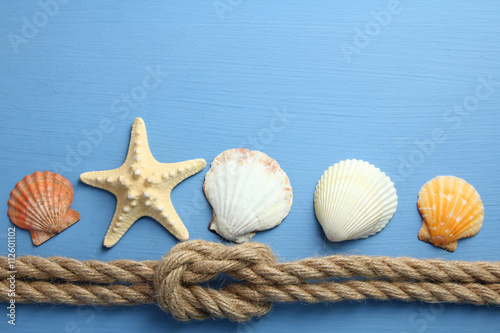knot with different seashells on blue wooden background