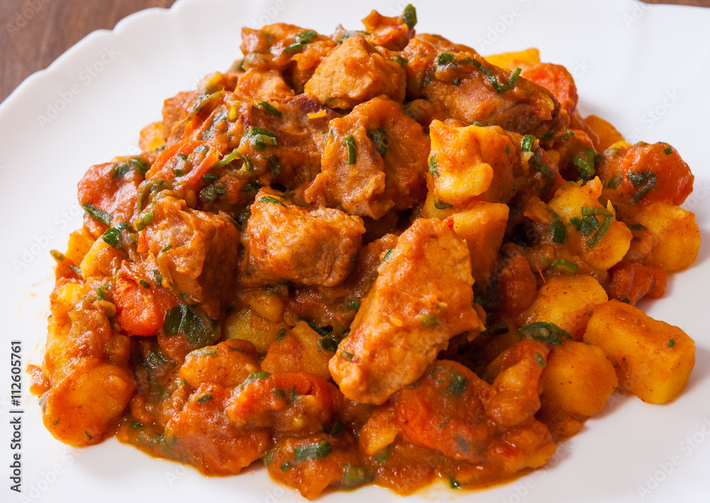 Stewed meat with vegetables in a plate on wooden table Stewed meat with vegetables in a plate on wooden table