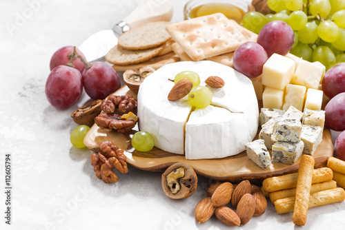 camembert, grapes and snacks on a white table, closeup