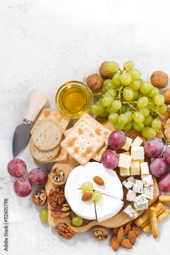 camembert, grapes and snacks on a white table, vertical