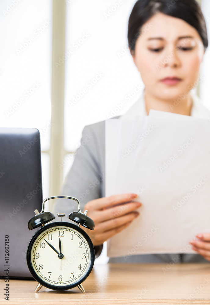 Businesswoman with papers over table with alarm clock laptop - obrazy, fototapety, plakaty 
