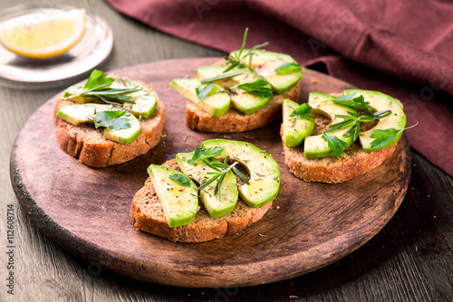 Toast with avocado, herbs on wooden board