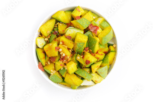 Organic sliced Indian Mango  Mangifera indica   seasoned with turmeric  salt and red chili pepper in white bowl. Isolated on white background.Top view.