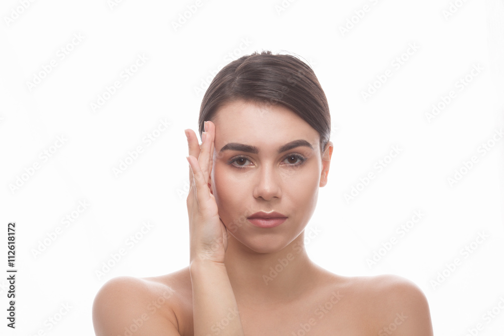 Closeup portrait of beautiful woman looking at camera in studio. Pretty and young lady touching her face over white background.