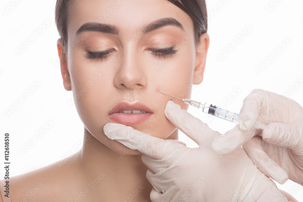Doing botox injection. Beautiful young shirtless woman keeping eyes closed while doctors hand making injection in face. Doing botox injection. Beautiful young shirtless woman keeping eyes closed while doctors hand making injection in face.