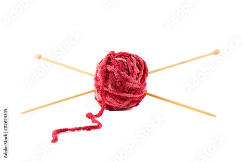 Knitting needles pierce a ball of red wool.