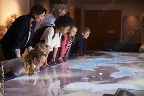 Pupils On School Field Trip To Museum Looking At Map