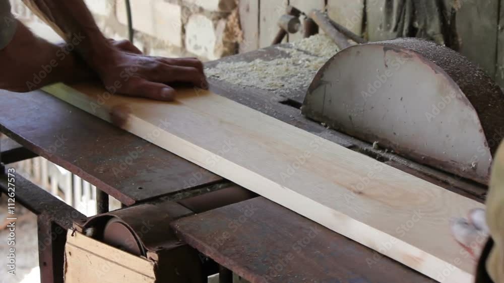 Two poor carpenter handle wooden Board on an old machine, not observing safety