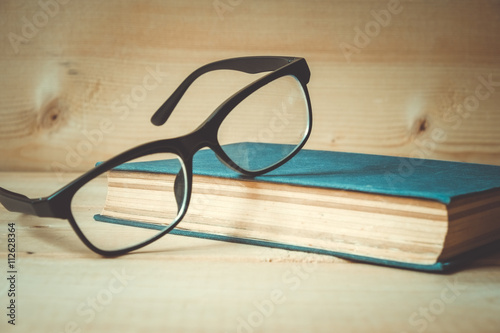 Old books and glasses on a wooden table with filter effect retro