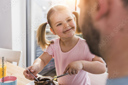 Grinning girl with smeared mouth looking at father photo