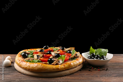 Delicious tasty pizza with ingredients on wooden table