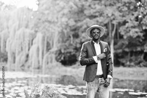 Portrait of stylish rich black man at blue jacket, hat and sungl