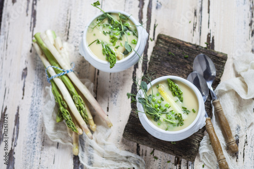 Cream of white asparagus soup garnished with white and green asparagus spears, pea shots and chives photo