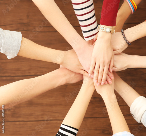 Group of people hands together on wooden background