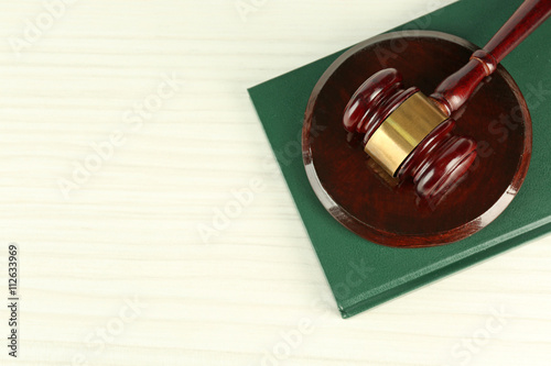 Gavel and book on light wooden background