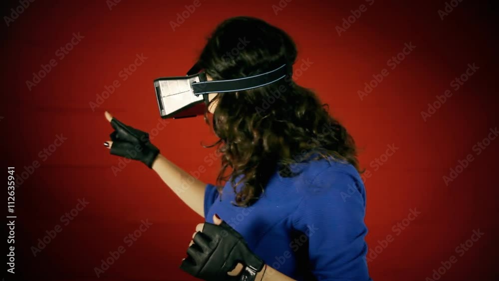 A pretty woman wearing a virtual reality headset and wired gloves, having an amazing experience inside a VR world. A pretty woman wearing a virtual reality headset and wired gloves, having an amazing experience inside a VR world.