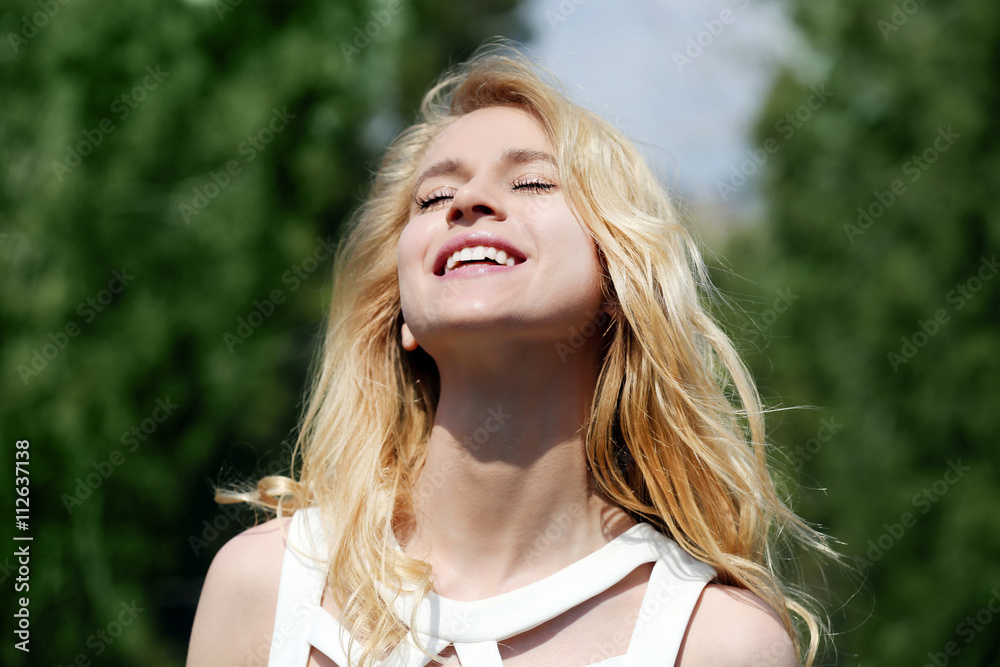 Naklejka premium Blonde woman with closed eyes and open mouth enjoying sunlight outdoors, expressing happiness and freedom in nature, she expresses happiness and freedom in a natural setting