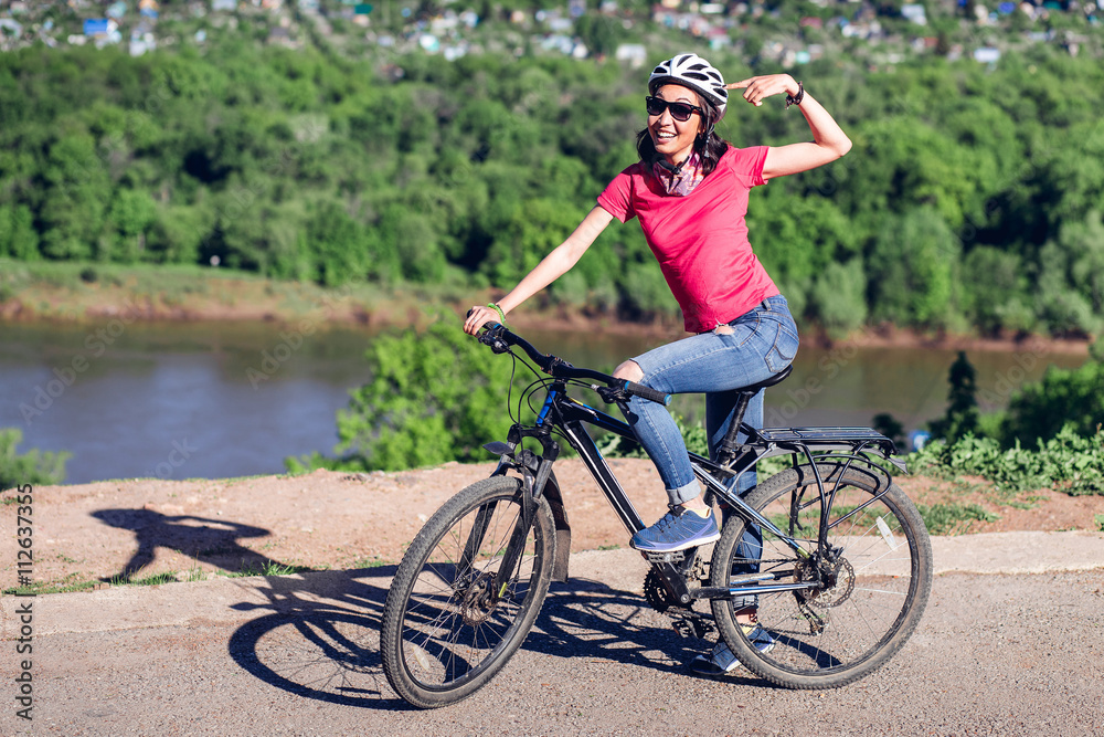 Bike helmet - woman putting biking helmet on during bicycle ride.