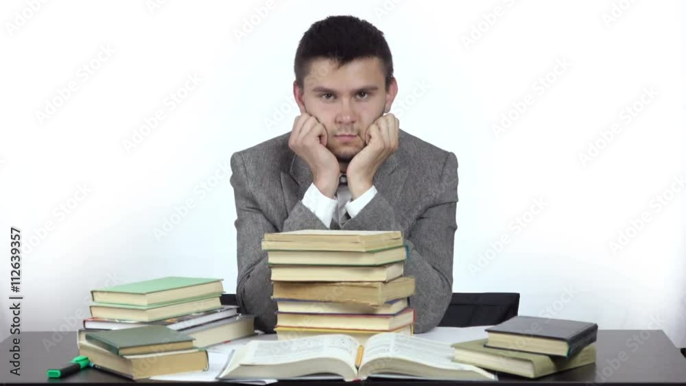 young tired student is sitting at table surrounded by books. 4k people stock footage clip at white background.
young tired student is sitting at table surrounded by books. 4k people stock footage clip at white background.