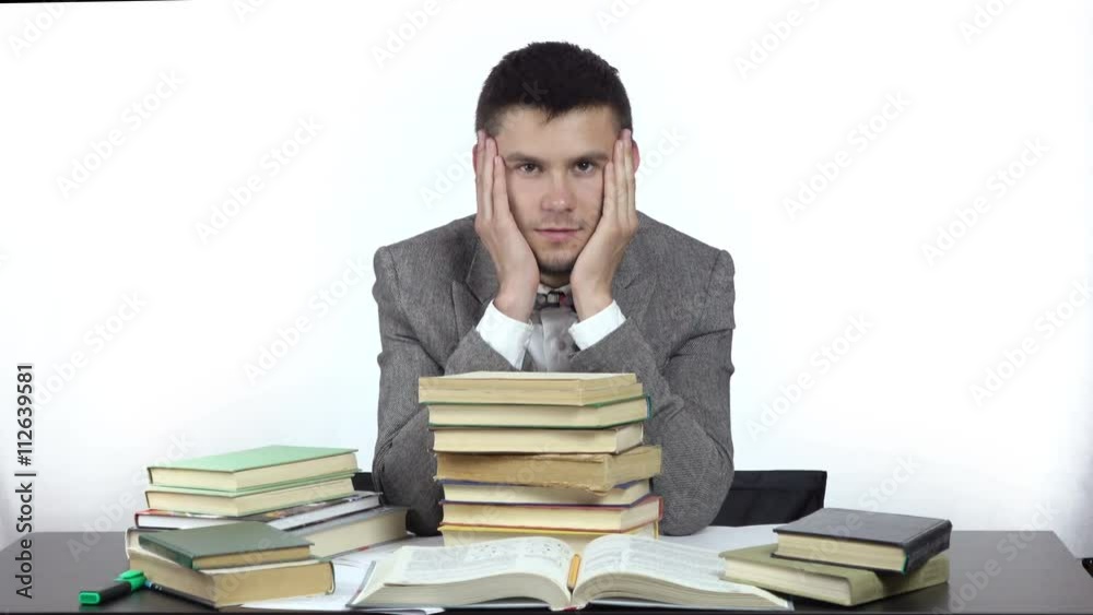 young tired student is sitting at table surrounded by books. 4k people stock footage clip at white background.
young tired student is sitting at table surrounded by books. 4k people stock footage clip at white background.