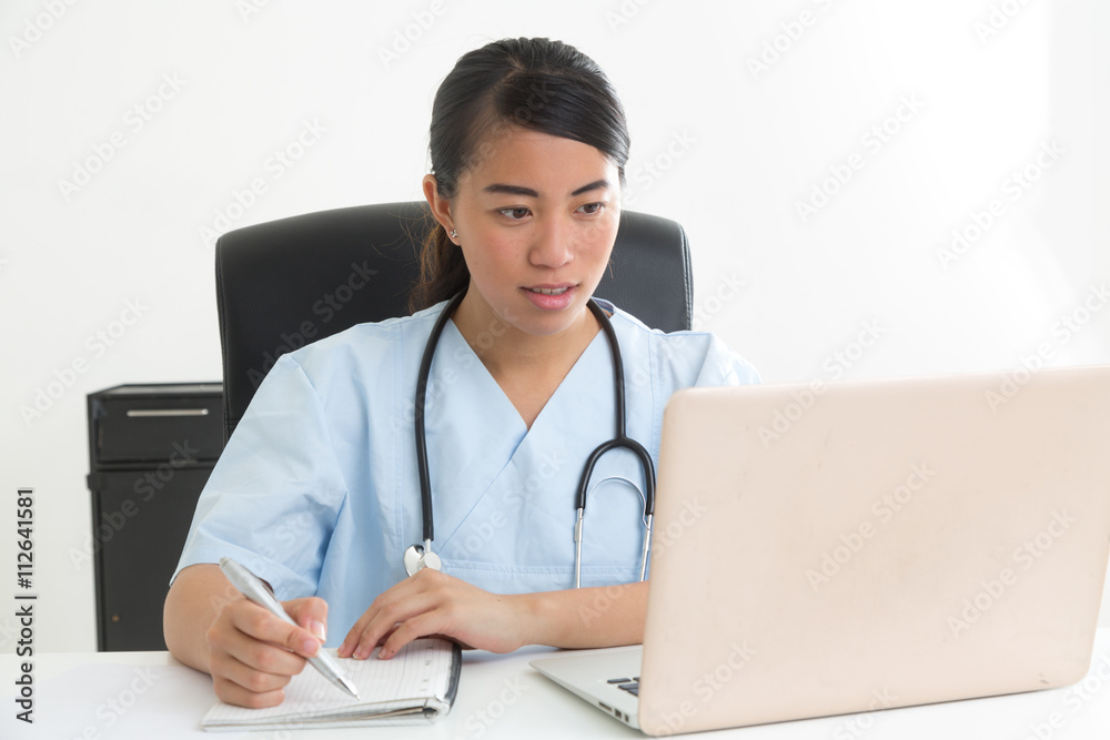 Young asian medical assistant sitting at desk and taking notes Young asian medical assistant sitting at desk and taking notes
