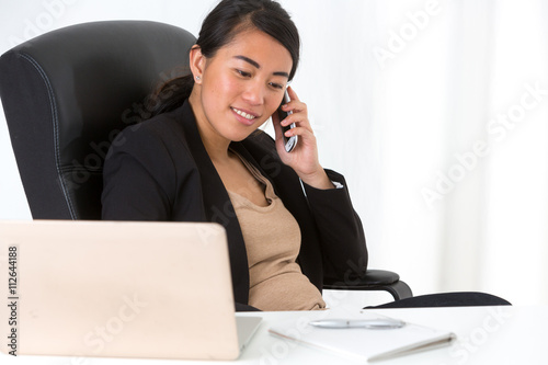 Young asian businesswoman at telephone in office