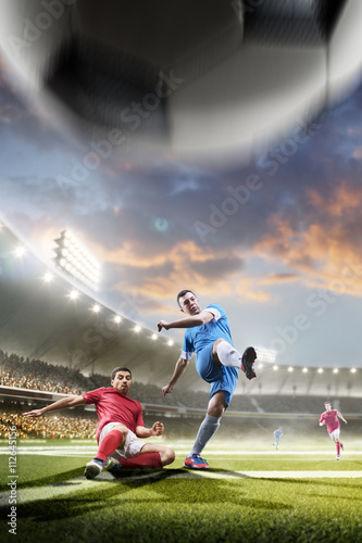 Soccer players in action on sunset stadium background