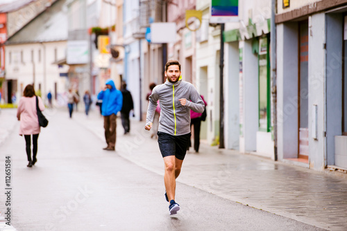 Young hipster man running in town, main street