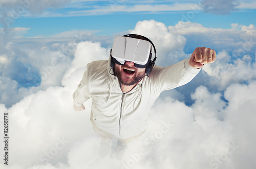 Man in virtual reality glasses flying among clouds