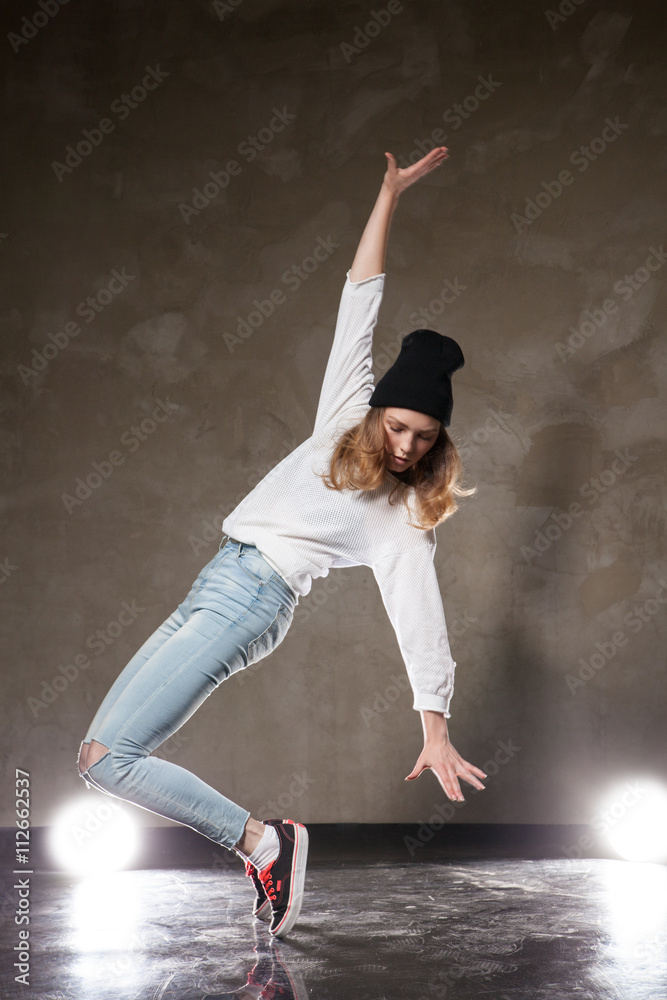 Young woman in black hat dancing on tiptoe