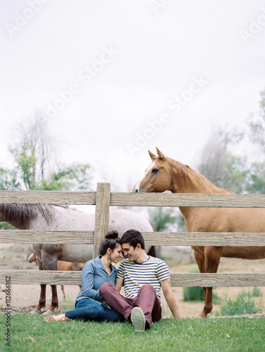 Couple sitting by fence of a horse paddock