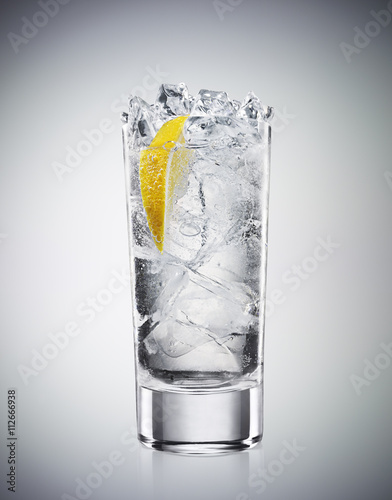 Glass of refreshing drink soda and lemon in a highball glass on graded background photo