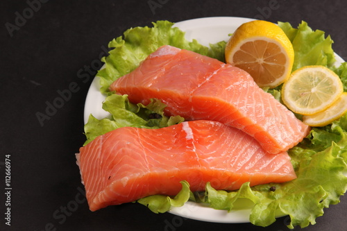 salmon on a plate with salad and lemon