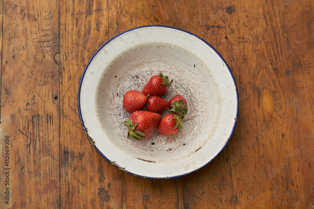 strawberries on rustic plate on wooden table strawberries on rustic plate on wooden table