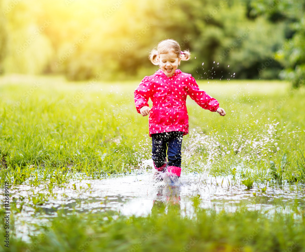 happy child girl running and jumping in puddles after rain Stock-Foto ...